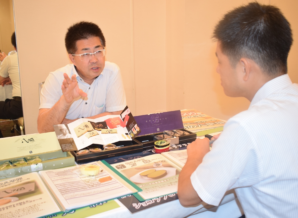 国内のバイヤーに自社商品の特徴や魅力を紹介する県内企業の担当者(左)=11日、青森市
