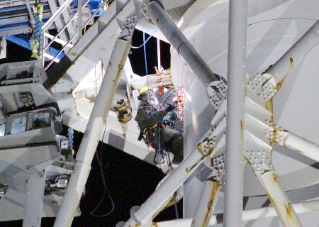 福島第1原発1、2号機の共用排気筒の解体作業で、電動のこぎりで排気筒を切断する作業員(中央)=3日午後、福島県大熊町(東京電力提供)