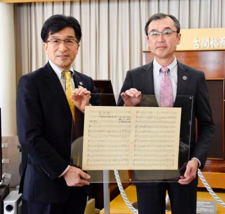 JICAの担当者から、古関裕而さんが作曲した青年海外協力隊の隊歌の楽譜を受け取る福島市の木幡浩市長(左)=9日、福島市