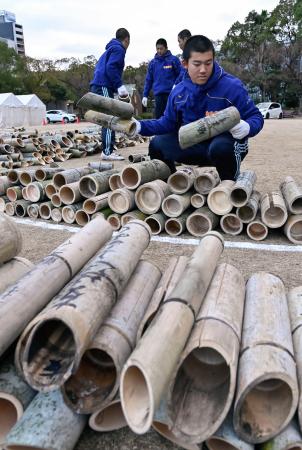 阪神大震災の追悼行事が行われる神戸市の公園「東遊園地」で竹灯籠を並べる神港学園高の野球部員ら=15日午後
