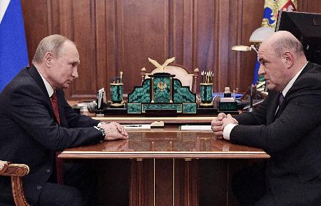 15日、モスクワのクレムリンで会談するロシアのプーチン大統領(左)とミシュスチン連邦税務局長官(ロシア大統領府提供・タス=共同)