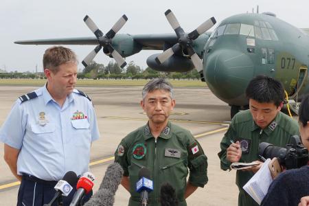 航空自衛隊のC130輸送機(奥)でオーストラリア東部リッチモンドに到着し、取材に応じる太田将史1等空佐(中央)=16日(共同)