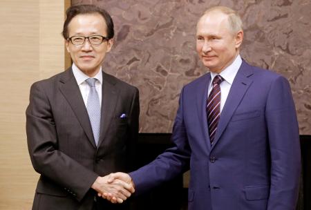 16日、モスクワ郊外のロシア大統領公邸にプーチン大統領(右)を表敬訪問し、握手する北村滋国家安全保障局長(タス=共同)