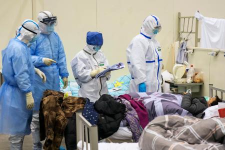 中国・武漢市内のホールに臨時に設置された病院で、新型肺炎患者に対応する医療従事者ら=10日(新華社=共同)