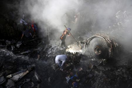 パキスタン航空(PIA)の旅客機が墜落した現場で生存者を捜すボランティアたち=22日、パキスタン・カラチ(AP=共同)