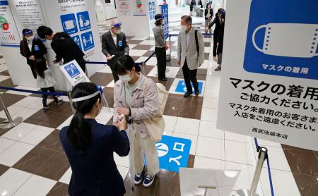 生活必需品を扱う売り場を再開した百貨店、西武池袋本店の入り口で検温を受ける来店客=23日午前、東京都豊島区