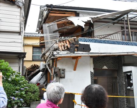 住宅に突っ込んだ乗用車(左下)=31日午後、和歌山市