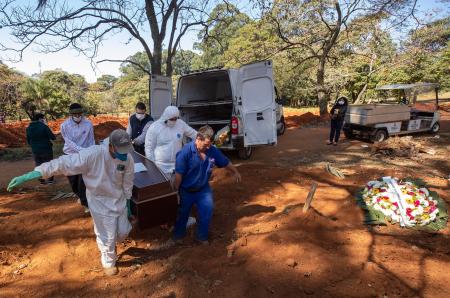ブラジル・サンパウロの墓地で、防護服を着て新型コロナ感染死者の棺おけを運ぶ人たち=5月28日(AP=共同)