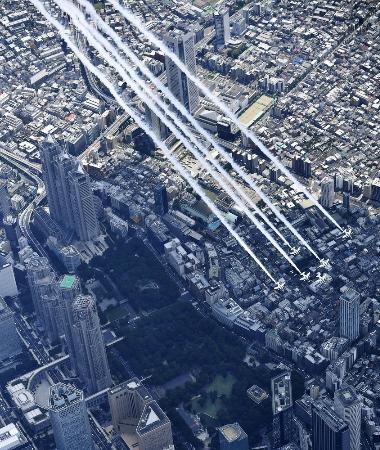 東京都庁(左)上空を飛行する航空自衛隊のブルーインパルス=5月29日、東京都新宿区(共同通信社ヘリから)