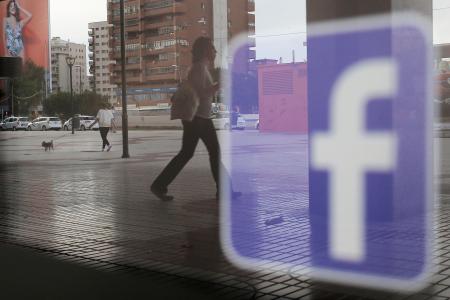 店舗のウインドーに映るフェイスブックのロゴ=2018年、スペイン・マラガ(ロイター=共同)