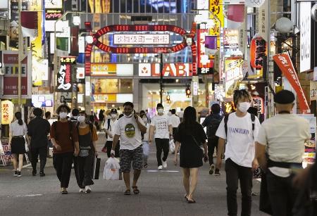 東京・新宿の歌舞伎町をマスク姿で行き交う人たち=7月21日夜