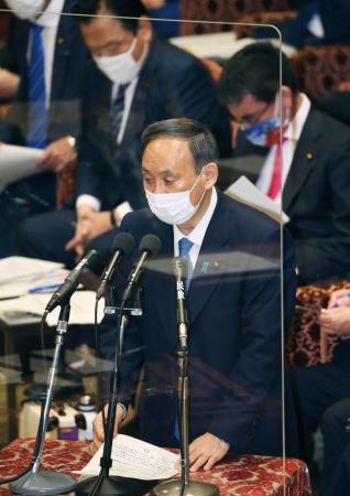 衆院予算委で答弁する菅首相。新型コロナ感染対策のためアクリル板が演台の前に置かれた=25日午前